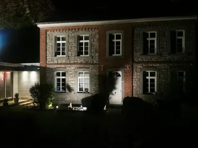 a brick house with a white door at night at Ferienwohnung in einem alten Bauernhaus in Lontzen