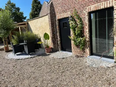 a patio with a table and chairs next to a brick building at Het Koerhuis in Kinrooi