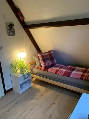 a bed in a room with a lamp and a plant at La Casita E41 in Lanaken