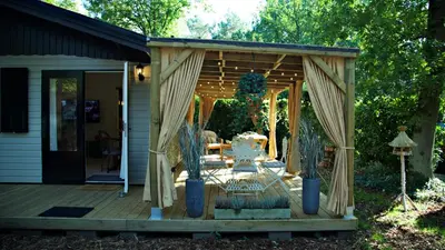 a pergola on a wooden deck with a table at Chalet Maurice in Zutendaal