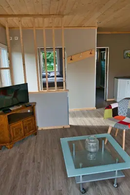 a living room with a tv and a glass table at Le gîte de l'écurie des Saules in Plombières