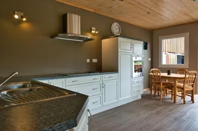 a kitchen with white cabinets and a table with chairs at Le gîte de l'écurie des Saules in Plombières