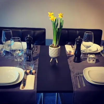 a table with glasses and a vase with yellow flowers on it at Grey House in Olne