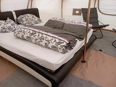 a bed with black and white pillows on it at Natuur-like Glamping in Bosland in Pelt