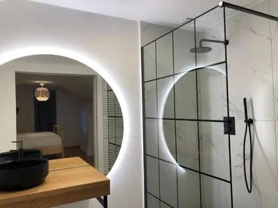 a bathroom with a glass shower door and a wooden table at L'Entre-Temps in Xhendelesse