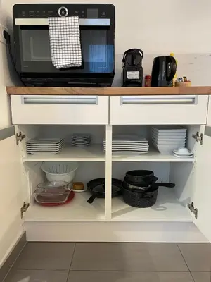 a microwave oven sitting on top of a cabinet with dishes at L'Entre-Temps in Xhendelesse