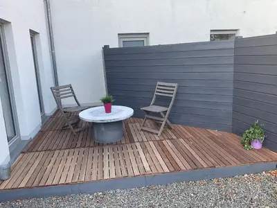 a patio with two chairs and a table on a deck at L'Entre-Temps in Xhendelesse