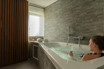 a woman sitting in a bath tub in a bathroom at L'Entre-Temps in Xhendelesse