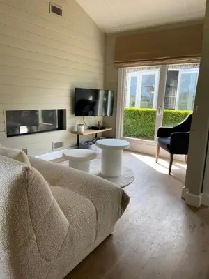 a living room with a couch and a tv at Chalet Eau Vive Meinekom in Maaseik