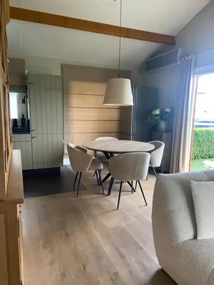 a dining room with a table and chairs and a couch at Chalet Eau Vive Meinekom in Maaseik