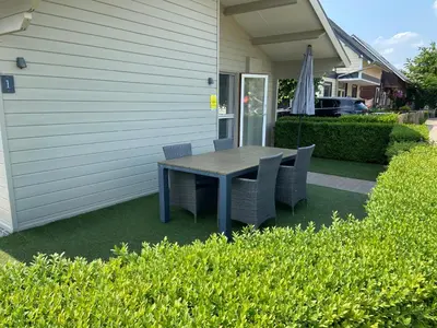 a table and chairs on a lawn outside a house at Chalet Eau Vive Meinekom in Maaseik