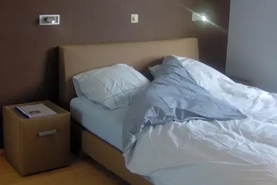 a bed with white sheets and pillows and a night stand at De Zilveren Helm in Halen