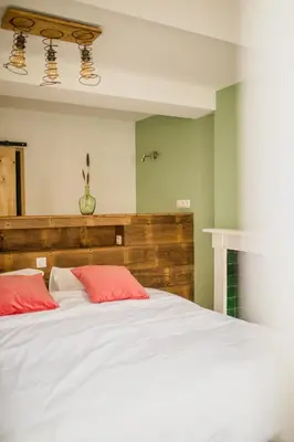 a bedroom with a large white bed with red pillows at Le Mayou in Mortroux