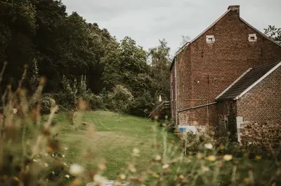 an old brick barn in a field with trees at Le Mayou in Mortroux