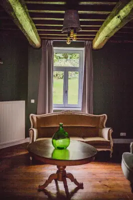 a living room with a table and a couch and a window at Le Mayou in Mortroux
