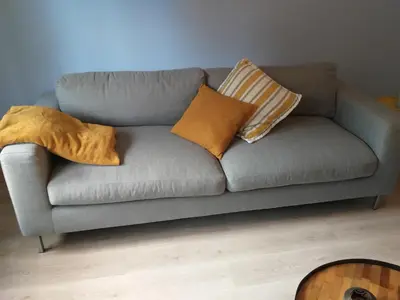a gray couch with pillows on it in a living room at La Maison de Sidonie in Jalhay