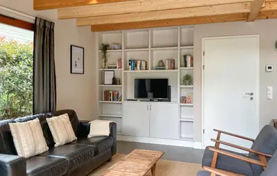 a living room with a black leather couch and a tv at Sonnevijver Vijverdorp-Waterl in Bovenwezet