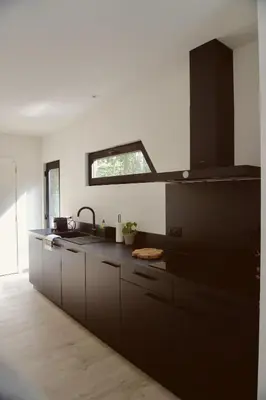 a kitchen with black cabinets and a sink at Sweet Valley Madeleine in Zutendaal