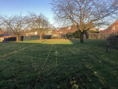 a field of grass with a tree and a fence at 14P 5B Villa de Poothoeve with Sauna and beautiful garden in Bilzen