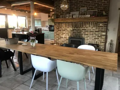 a large wooden table with white chairs and a fireplace at 14P 5B Villa de Poothoeve with Sauna and beautiful garden in Bilzen
