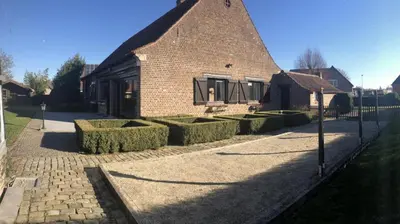 a brick house with hedges in front of it at 14P 5B Villa de Poothoeve with Sauna and beautiful garden in Bilzen