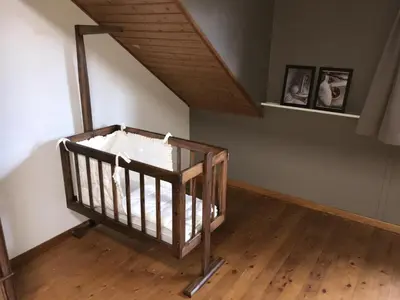 a crib in a room with a wooden floor at 8P 3B Cozy vacation home for 8 persons in Heers in Heers