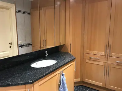 a bathroom with a sink and wooden cabinets at Vakantiehuis Martien in Peer
