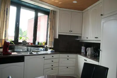 a kitchen with white cabinets and a sink and a window at Vakantiehuis Martien in Peer