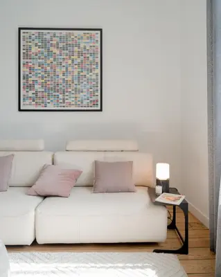 a white couch in a living room with a painting on the wall at La Maison de Chestret in Liège