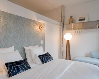a bedroom with a white bed with two blue pillows at La Maison de Chestret in Liège