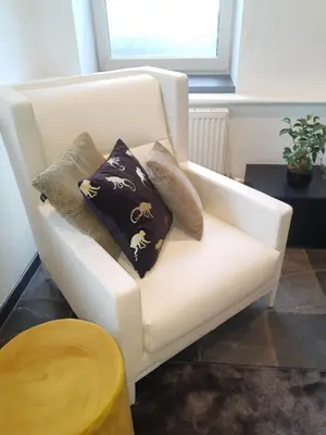 a white chair with pillows on it in a room at Vakantiewoning 'De Vlaamse Aap' in Dilsen-Stokkem