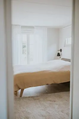 a bed in a white room with a window at Kipdorp39 in Bree