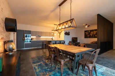 a kitchen and dining room with a wooden table and chairs at GUILLEMINS STATION FLATS in Liège