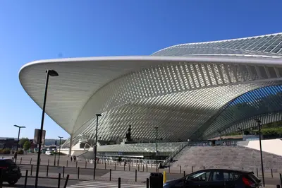 a large white building with a car parked in front of it at GUILLEMINS STATION FLATS in Liège