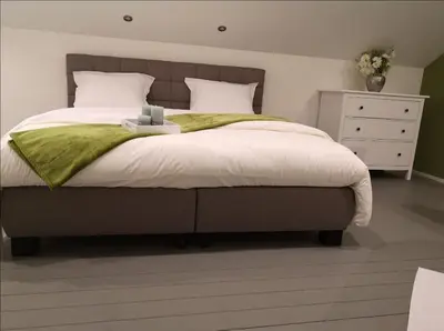 a bedroom with a bed with a green blanket and a dresser at Ô'bel Écrin in Aubel