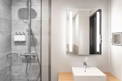 a bathroom with a shower and a sink and a mirror at Radisson Hotel Liege City Centre in Liège