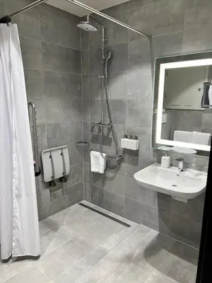 a bathroom with a sink and a shower with a mirror at Radisson Hotel Liege City Centre in Liège