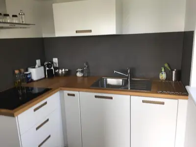 a kitchen with white cabinets and a sink at Le temps d’une balade. in Olne