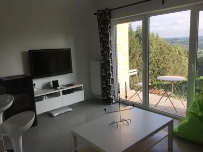 a living room with a tv and a large window at Le temps d’une balade. in Olne