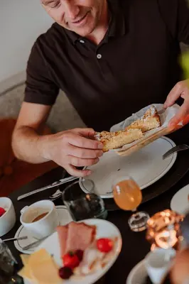 a man eating a slice of pizza on a table at B&B het Notarishuis - authentiek verblijf nabij Maastricht in Voeren