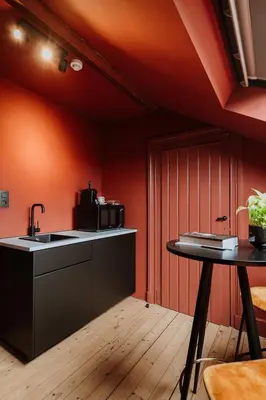 a kitchen with orange walls and a sink and a table at B&B het Notarishuis - authentiek verblijf nabij Maastricht in Voeren