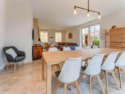 a dining room and living room with a wooden table and white chairs at Heers Retreat with Sauna in Heers