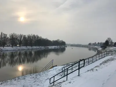 a river covered in snow with a fence next to it at Ons Maashuisje in Maaseik