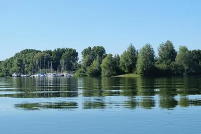 a view of a lake with trees and boats at Ons Maashuisje in Maaseik