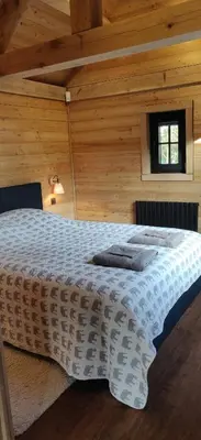 a bedroom with a large bed in a wooden room at Chalet Duras in Sint-Truiden