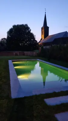 a reflection of a church in a pond in front of a church at Haspenhoeve Vakantiewoning in Herstappe