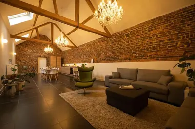 a living room with a couch and a brick wall at Haspenhoeve Vakantiewoning in Herstappe