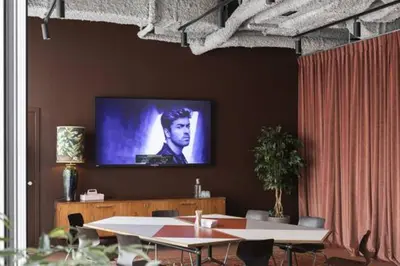 a room with tables and a tv on a wall at YUST Liege in Liège