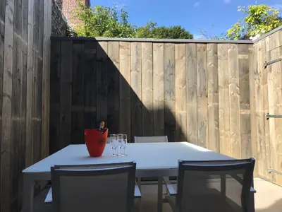 a white table with chairs and a vase on a fence at Gezellig stadshuisje met patio. in Tongeren