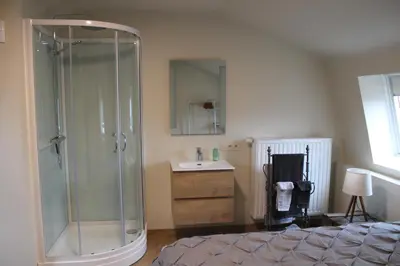 a bedroom with a glass shower and a sink at Gezellig stadshuisje met patio. in Tongeren